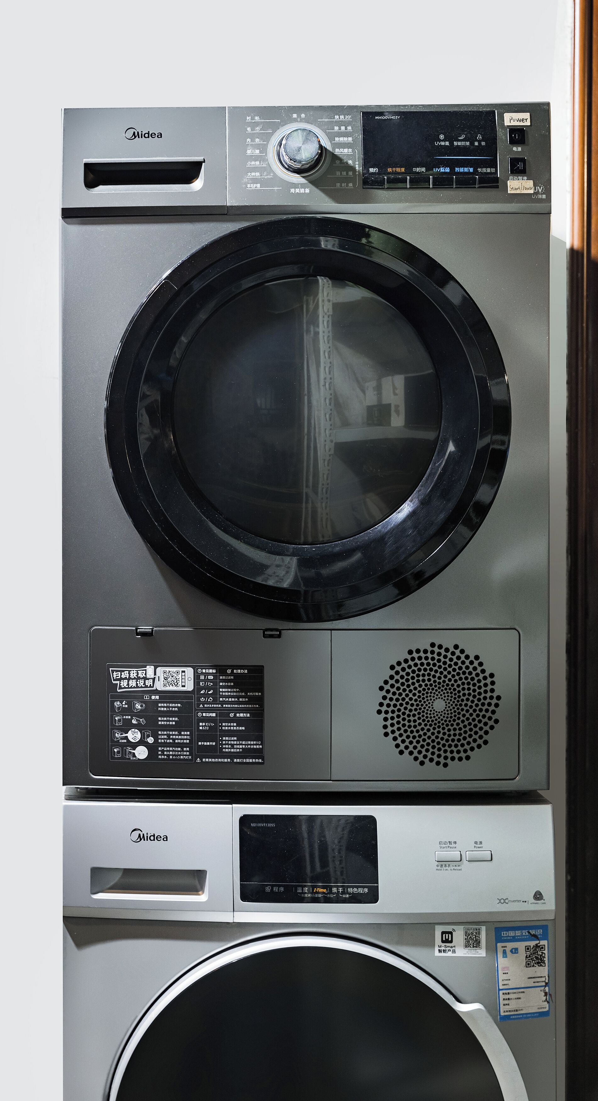 A stacked washer and dryer unit with control panels and a QR code.