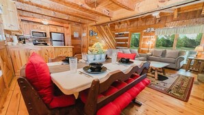 A cozy cabin interior with a dining area, kitchen, and living room.