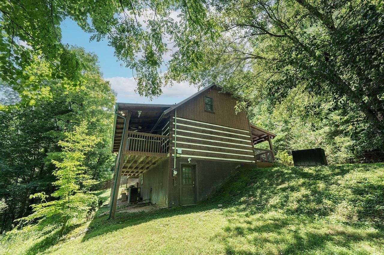 A rustic cabin with a wooden exterior, a covered porch, and a small attached shed.