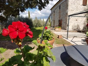 A courtyard with potted plants, a stone building, and a metal pergola. - La Canonica (Montalcino)