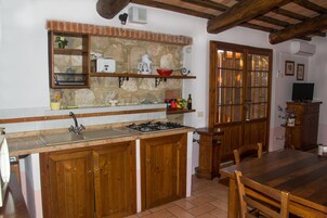 A kitchen with a stone backsplash, wooden cabinets, a gas stove, and a dining area with a wooden table and chairs.