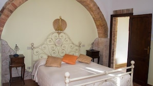 A bedroom with a bed, a nightstand, a lamp, and a mirror. - La Canonica (Montalcino)