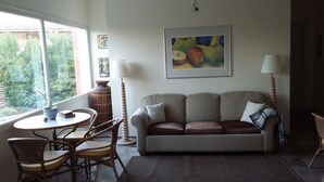 A living room with a sofa, chairs, a table, and a painting on the wall.