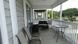 A covered porch with a seating area, including chairs and a table.