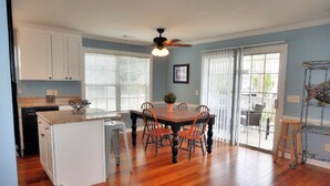 A kitchen with white cabinets, a wooden island, and a dining area with a table and chairs.