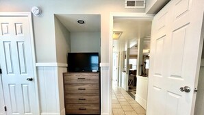 A hallway with a bed, a dresser, and a television in a room. - The Ocean House 6 Bedroom Home by RedAwning (Surfside Beach)