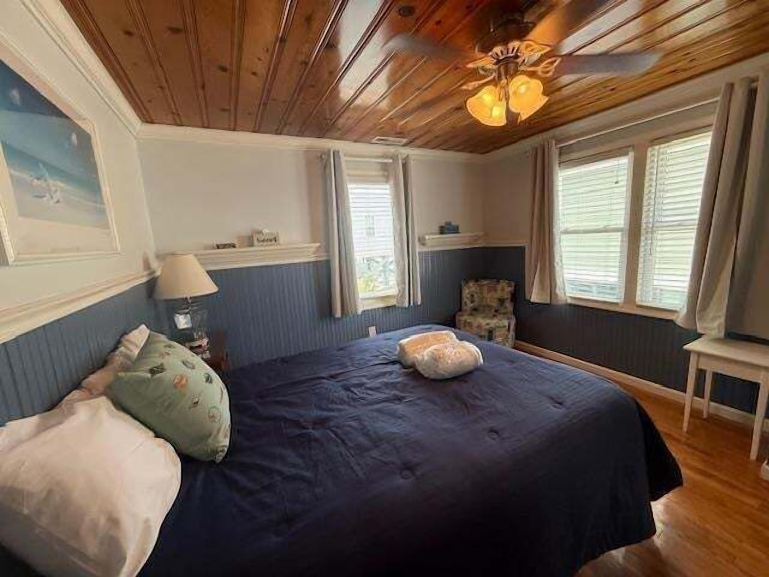 Una camera da letto con un letto, una sedia, una lampada e un ventilatore a soffitto.