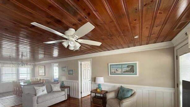 A spacious living room with hardwood floors, a ceiling fan, and a large window. - The Ocean House 6 Bedroom Home by RedAwning (Surfside Beach)
