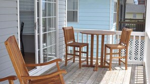 A wooden deck with a table and chairs, a white railing, and a window with blinds. - 5 By The Sea 5 Bedroom Home by RedAwning (Surfside Beach)
