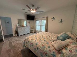 A bedroom with a bed, a dresser, a ceiling fan, and a window with curtains. - 5 By The Sea 5 Bedroom Home by RedAwning (Surfside Beach)