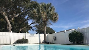 A swimming pool with clear water, surrounded by a white fence, trees, and a building. - 5 By The Sea 5 Bedroom Home by RedAwning (Surfside Beach)