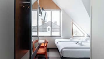 A modern hotel room with a desk, chair, and two beds.