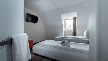 Una habitación de hotel moderna con cama, televisor, ventana y una pared de acento roja.