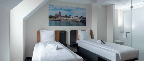A hotel room with two beds, a cityscape painting, a glass shower enclosure, and a white door.