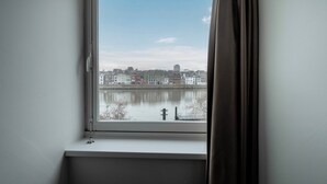 Una finestra con vista su un'acqua calma e edifici sull'altra sponda.