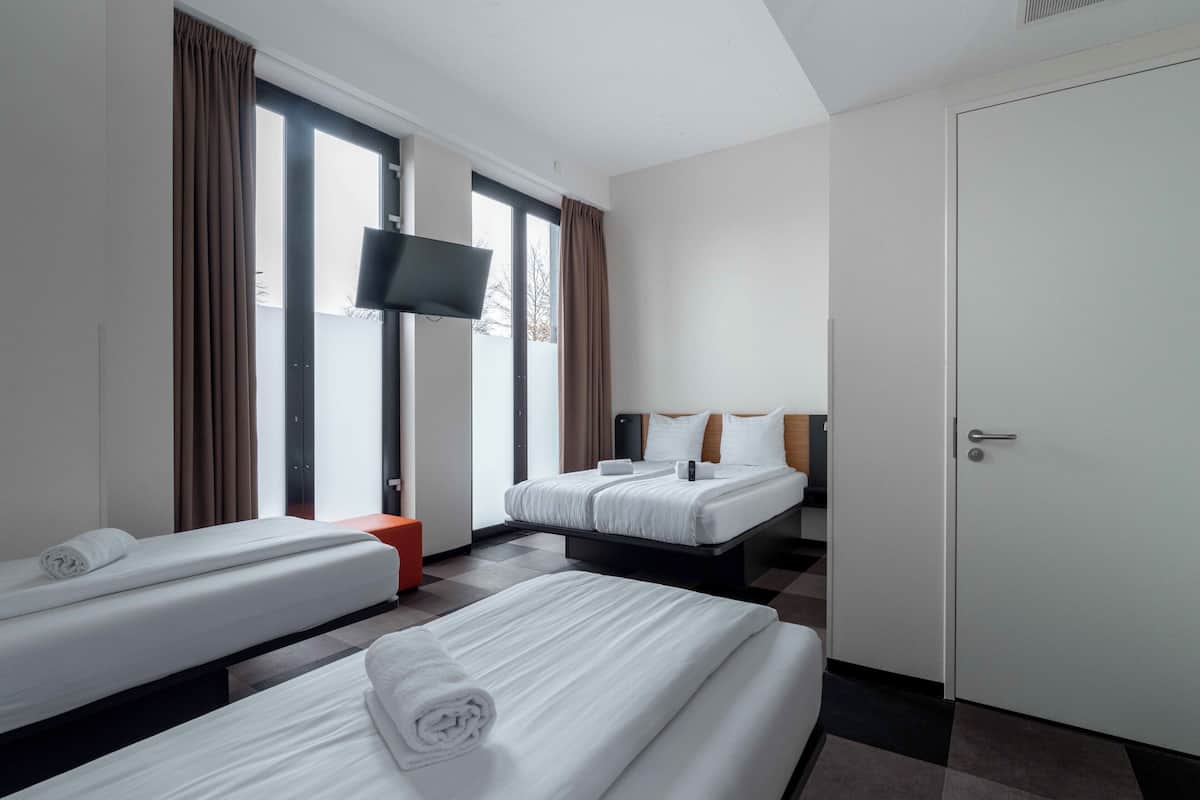 Ein Hotelzimmer mit zwei Betten, einem Fernseher und einer Tür.