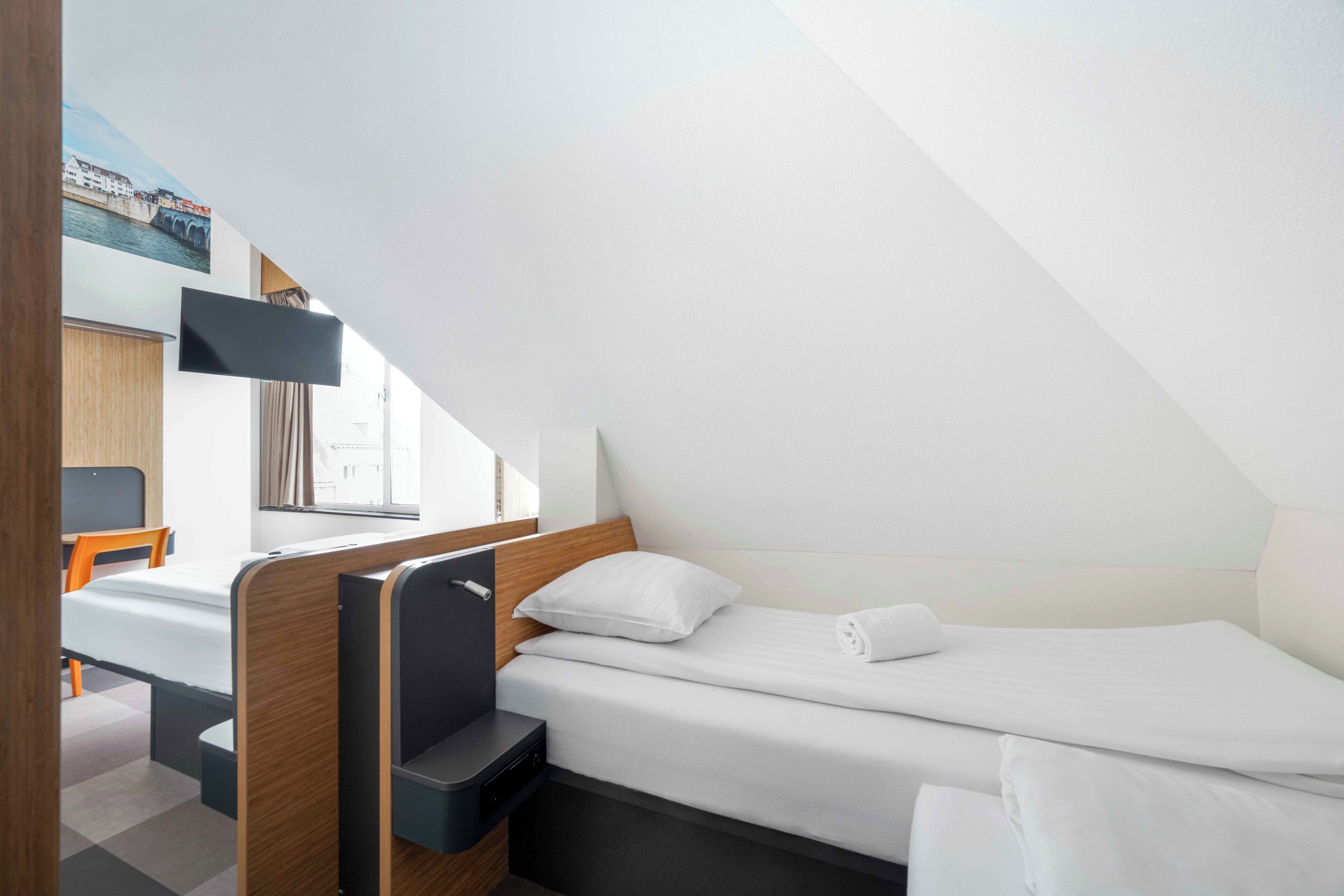 Een kleine, moderne kamer met een enkel bed, een bureau en een stoel.