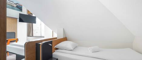 Una habitación pequeña y moderna con una cama individual, un escritorio y una silla.