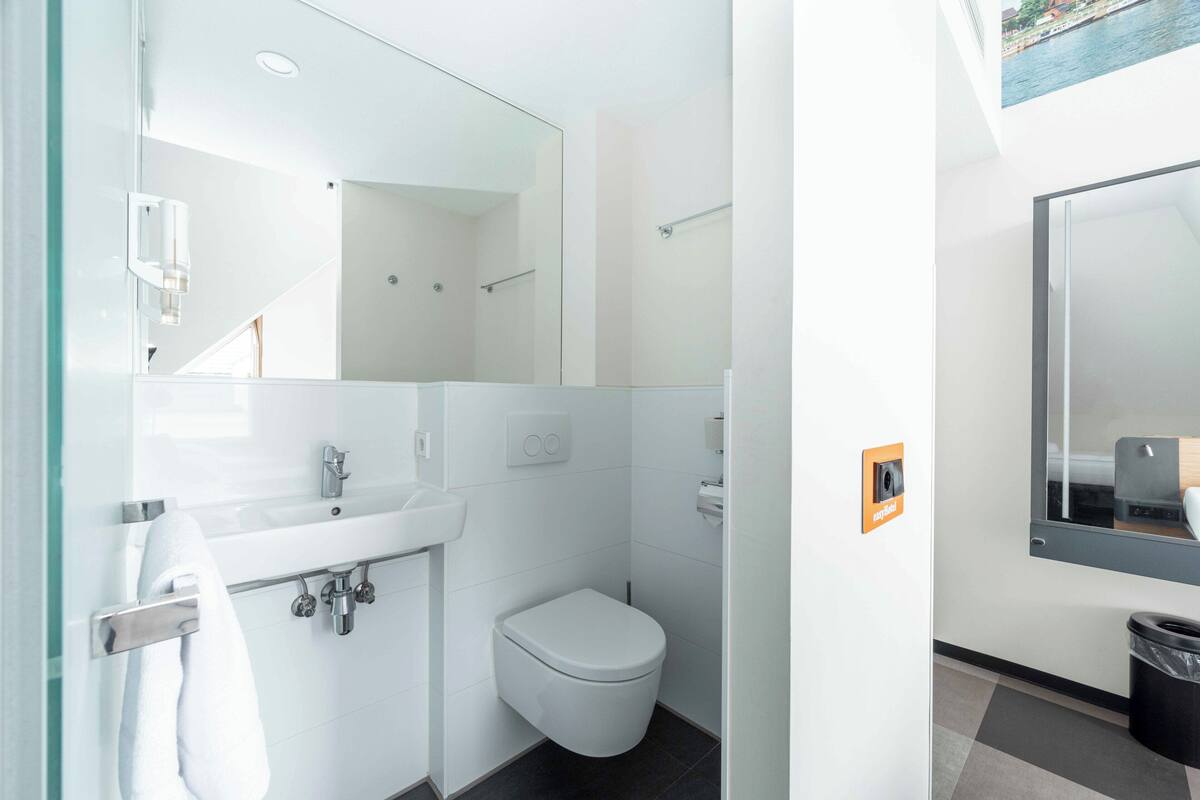 Ein modernes Badezimmer mit einer Duschkabine aus Glas, einem weißen Waschbecken und einer Toilette.