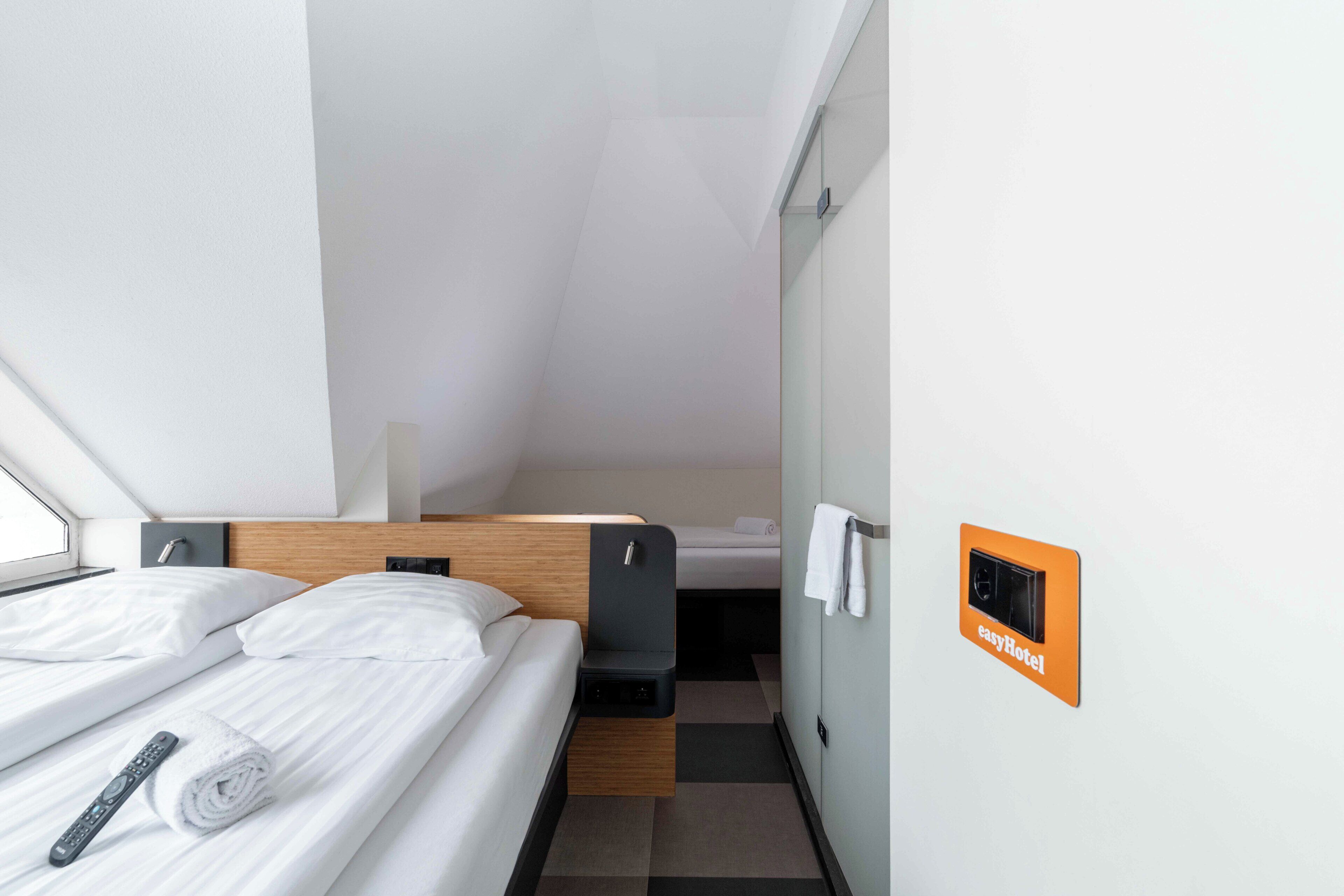 A modern hotel room with a bed, a control panel, and a towel.