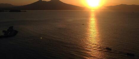 A sunset over a calm sea with mountains in the background.