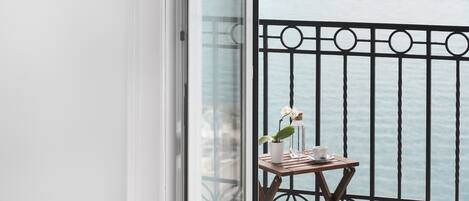 Un balcón con vista al mar, una mesita con una planta en maceta y una taza.