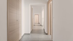 A long, narrow hallway with wooden doors on both sides, leading to a bright room at the end. - Lux B&B (Naples)