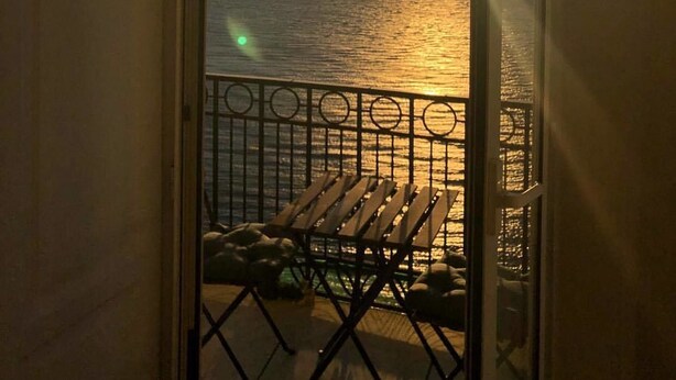 A balcony with a view of the sunset over the sea, a metal railing, and a wooden bench. - Lux B&B (Naples)