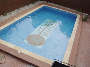 A rectangular swimming pool with a tiled border and a logo in the center. - Residence Niable (Abidjan)