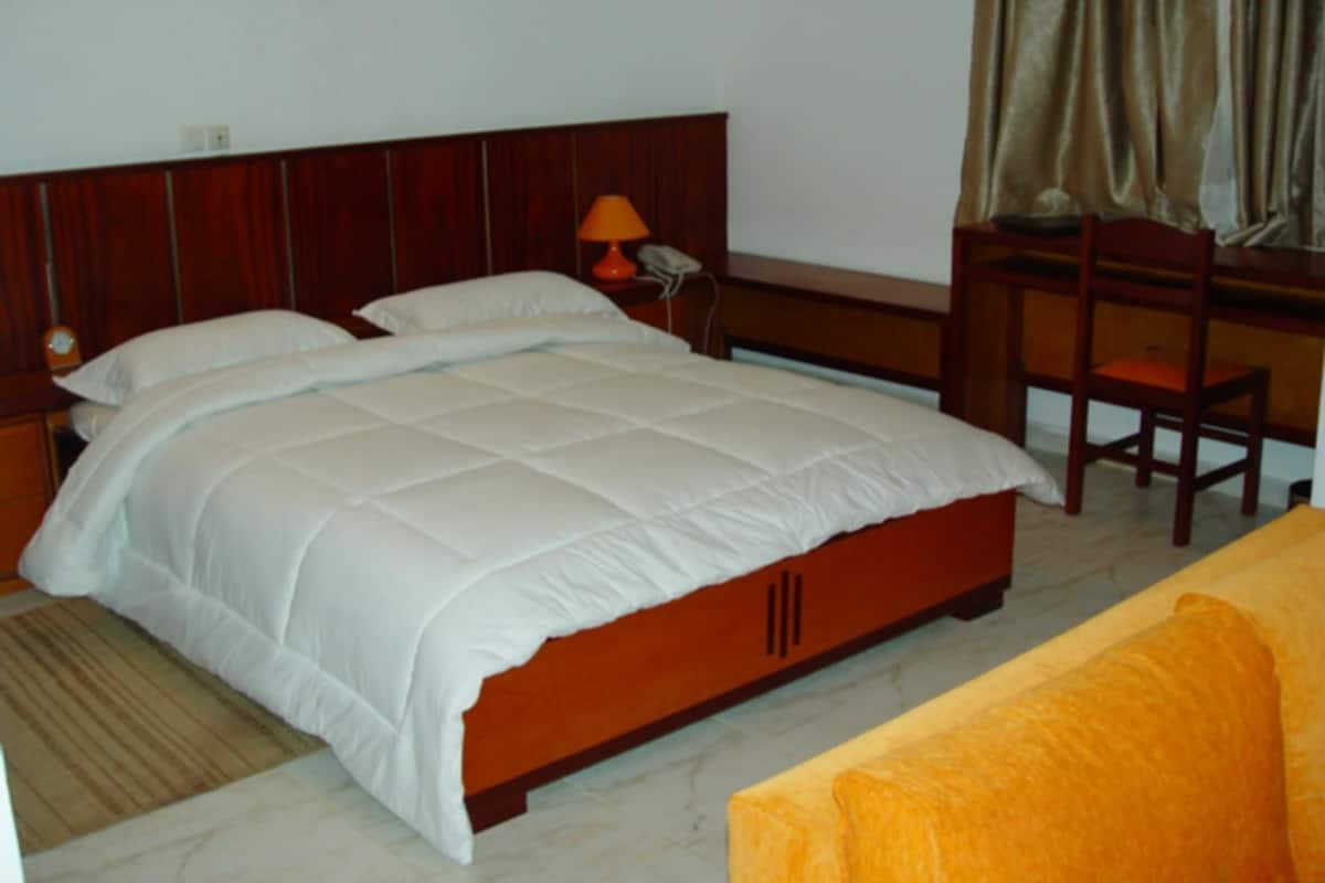 A bedroom with a bed, a desk, a chair, and a lamp.