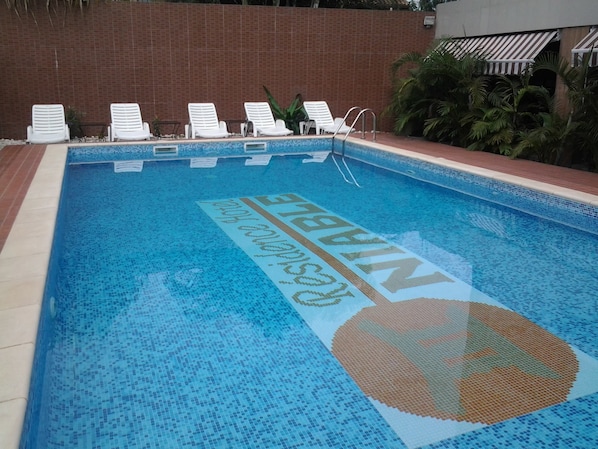 A swimming pool with a blue mosaic design and a large circular logo. - Residence Niable (Abidjan)