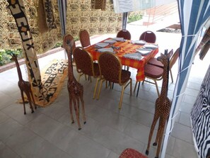 A dining area with a table set for six, surrounded by chairs, and decorated with giraffe statues. - Residence Niable (Abidjan)