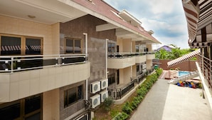 A multi-story hotel with balconies, air conditioning units, and a swimming pool area.