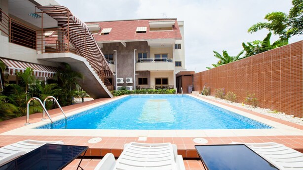 A swimming pool with lounge chairs and a staircase leading to an upper level of a building.