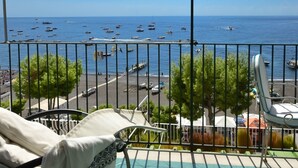 A balcony with a view of the sea, a chair, and a table.