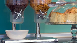Un buffet de petit-déjeuner comprenant une balance, un saladier et une vitrine réfrigérée où sont présentées des pâtisseries.