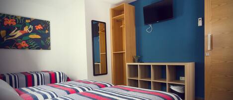 A bedroom with two beds, a TV, a wardrobe, and a mirror.