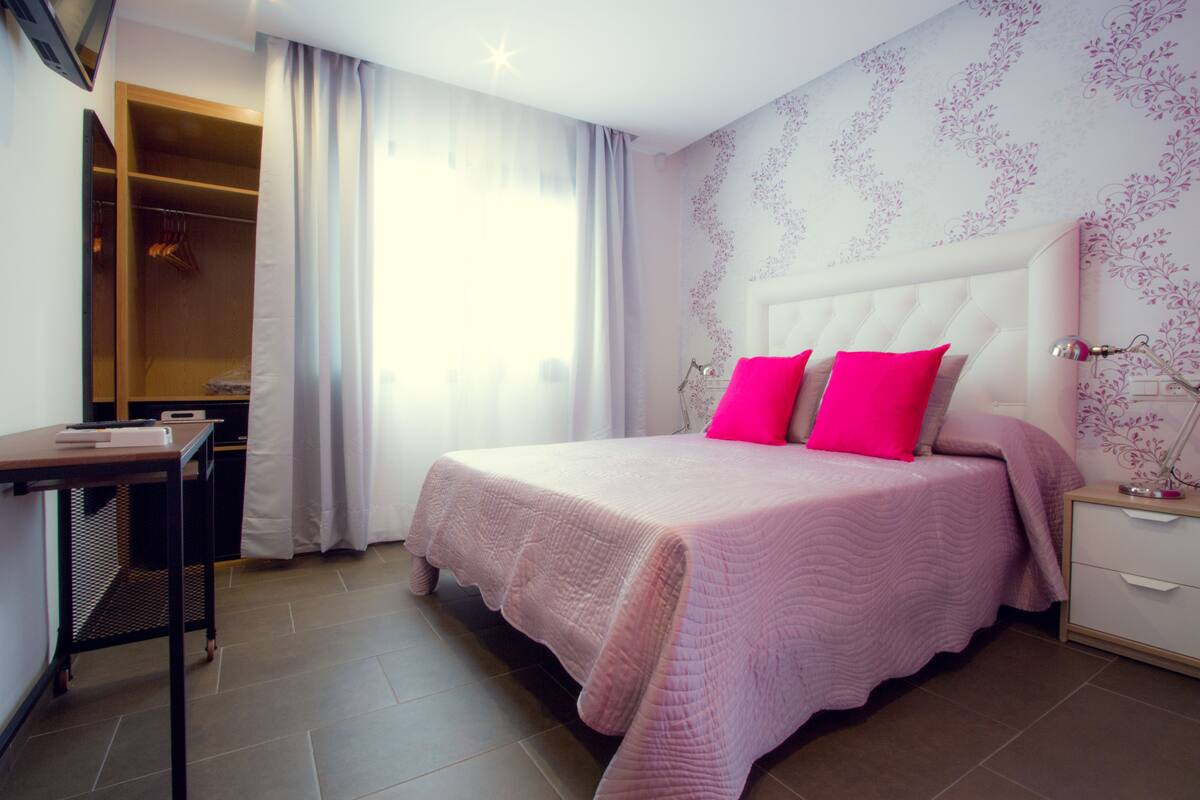 A bedroom with a bed, a desk, and a wardrobe.