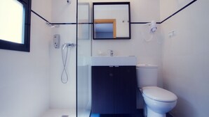 Une salle de bain moderne avec une douche à parois de verre, des toilettes blanches et un meuble en bois foncé.