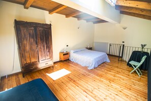A bedroom with wooden flooring, a bed, a wardrobe, a radiator, and a chair. - Agriturismo Turina by Connexion (Bricherasio)