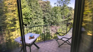 A balcony with a table and chairs, overlooking a forested area.
