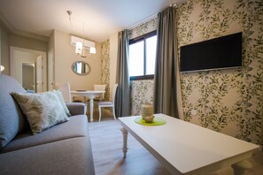 En moderne stue med sofa, spisebord og et fladskærms-tv monteret på væggen.