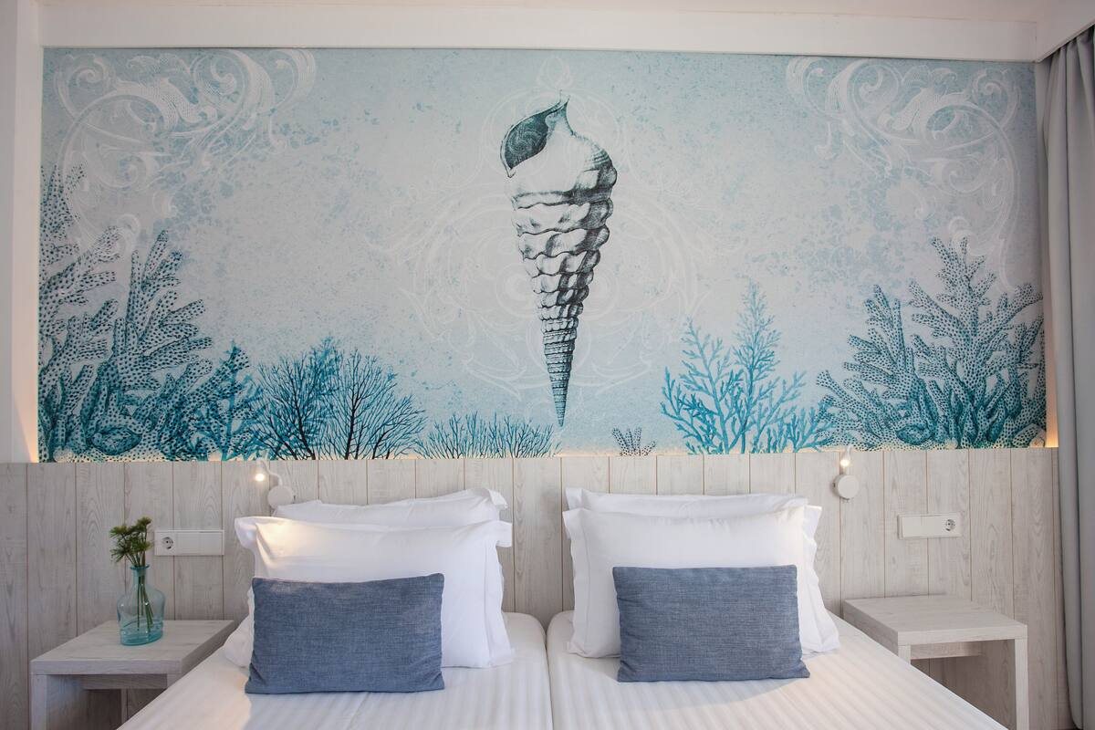 A hotel room with two beds, a mural of a sea creature, and a wooden headboard.