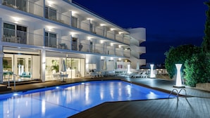 Un hotel de diverses plantes amb piscina, zona de seients a l'aire lliure i balcons.