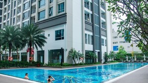 Ein modernes Hotel mit Schwimmbad, Palmen und blauem Himmel.