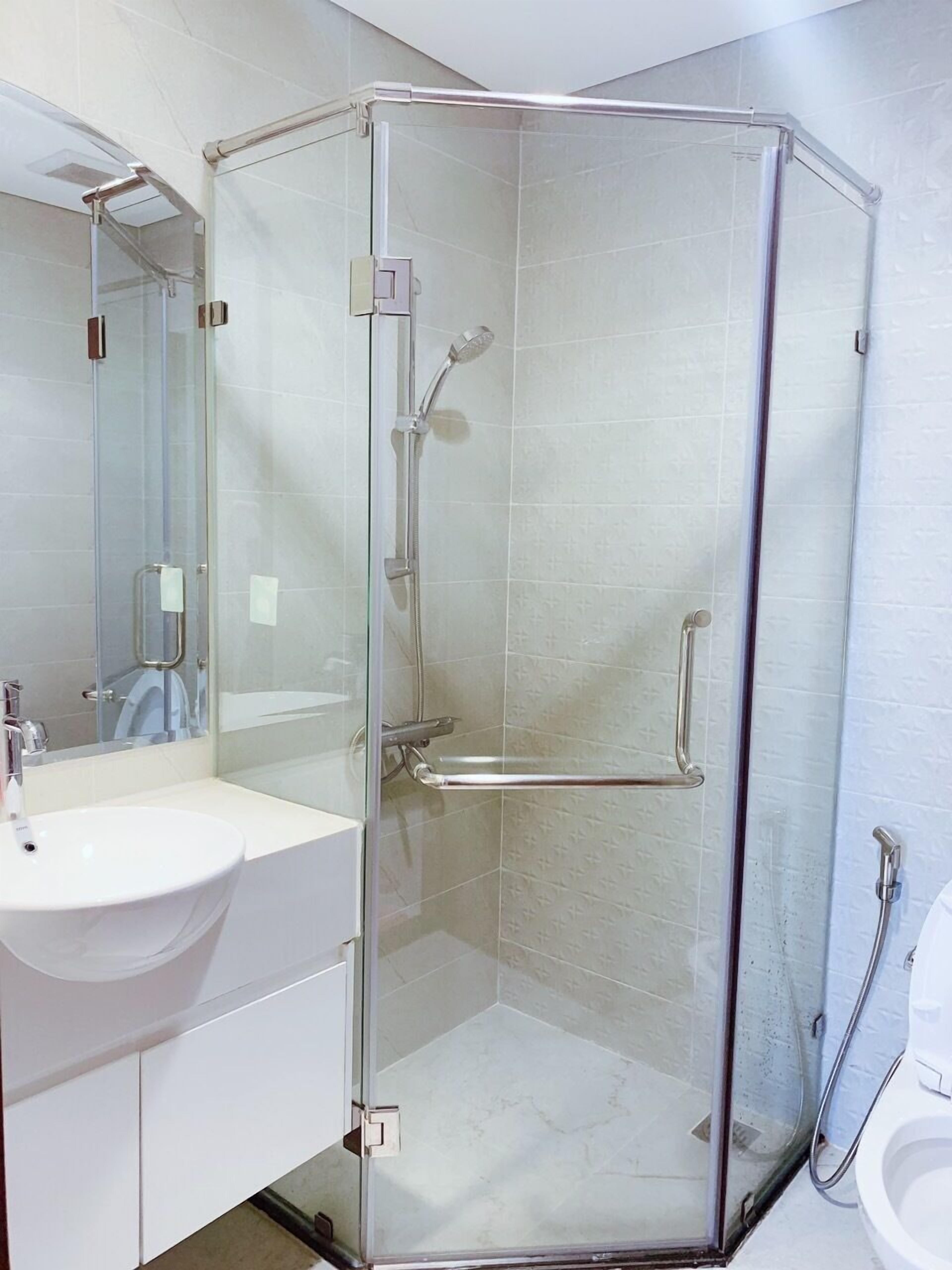 A modern bathroom with a glass-enclosed shower, a white sink, and a toilet.
