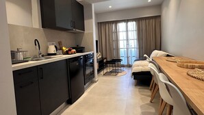 Een moderne keuken met donkere kastjes, een vaatwasser en een fornuis. Er is een eethoek met een houten tafel en stoelen.