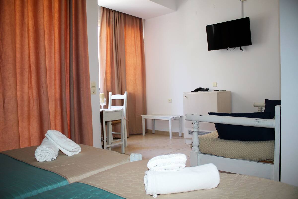 Una habitación de hotel con dos camas, un escritorio, una silla, un televisor y una mesita de noche.