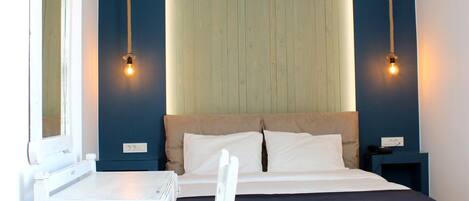A bedroom with a bed, a desk, and two bedside lamps.