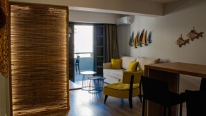 Een moderne woonkamer met een bank, gele fauteuils, een eettafel en een balkon met uitzicht.